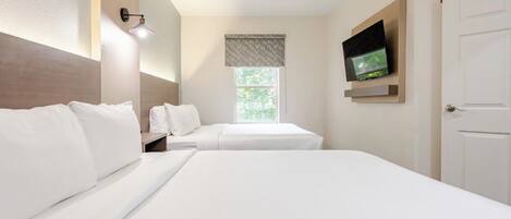 Une chambre d’hôtel avec deux lits, un téléviseur fixé au mur, une fenêtre donnant sur un paysage agréable et une porte.