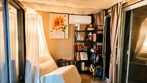 Ein gemütliches Zimmer mit einer gepolsterten Sitzecke, einem Bücherregal und einem großen Fenster mit Vorhängen.