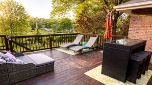 Eine Terrasse mit Korbmöbeln, einem Glastisch und einer Backsteinmauer.