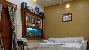A room with a marble floor, a ceiling fan, a chandelier, a fish tank, and a bed with white bedding. - KAPOOR SAHAB HOMESTAY it's a home away from home (Varanasi)