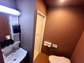 A compact bathroom with a sink, a toilet, and a mirror. - WINN hotel (Tokyo)
