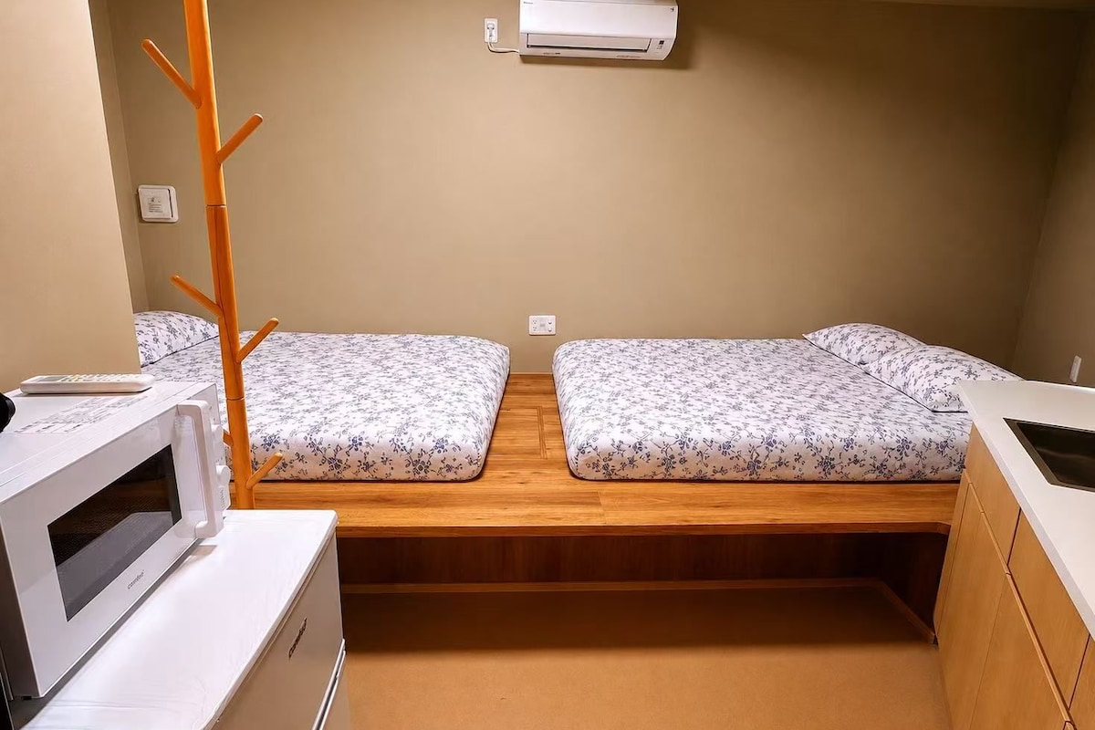 A compact room with two beds, a microwave, and a small table.