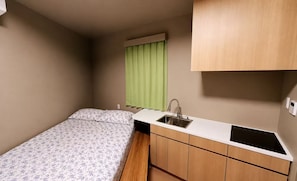 A compact room with a bed, a small kitchenette, and a window with curtains. - WINN hotel (Tokyo)