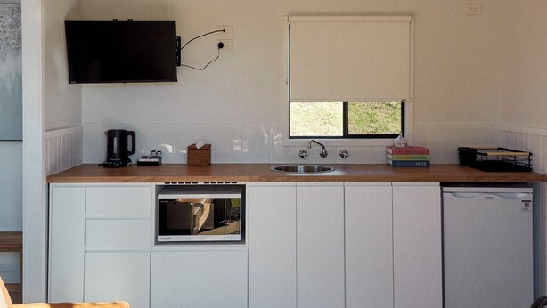 Cocina compacta con horno integrado, lavamanos y ventana.
