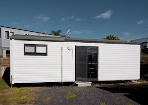 A small, single-story mobile home with a sliding door and a small window.