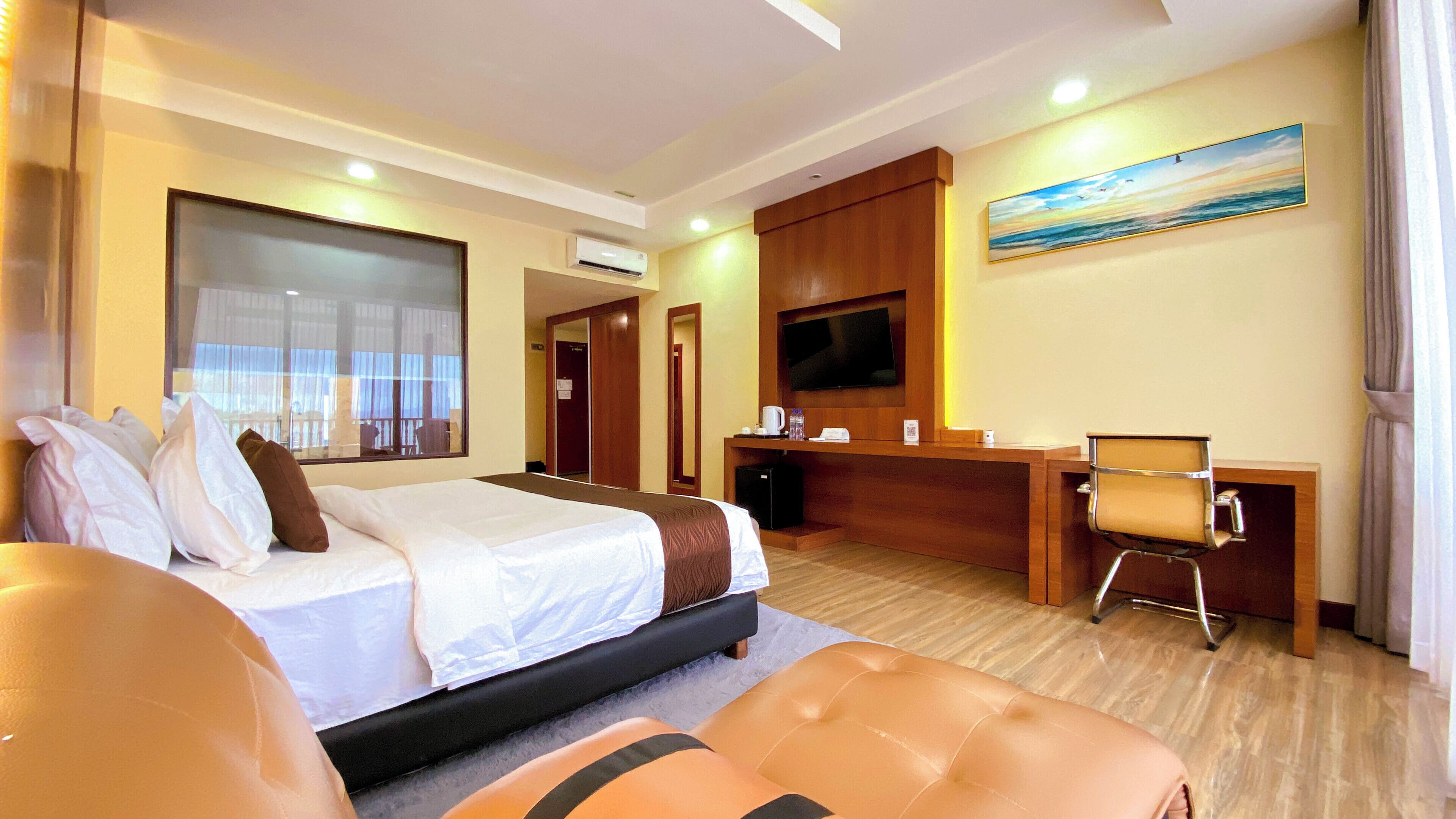 A hotel room with a bed, a desk, a television, and a large window.