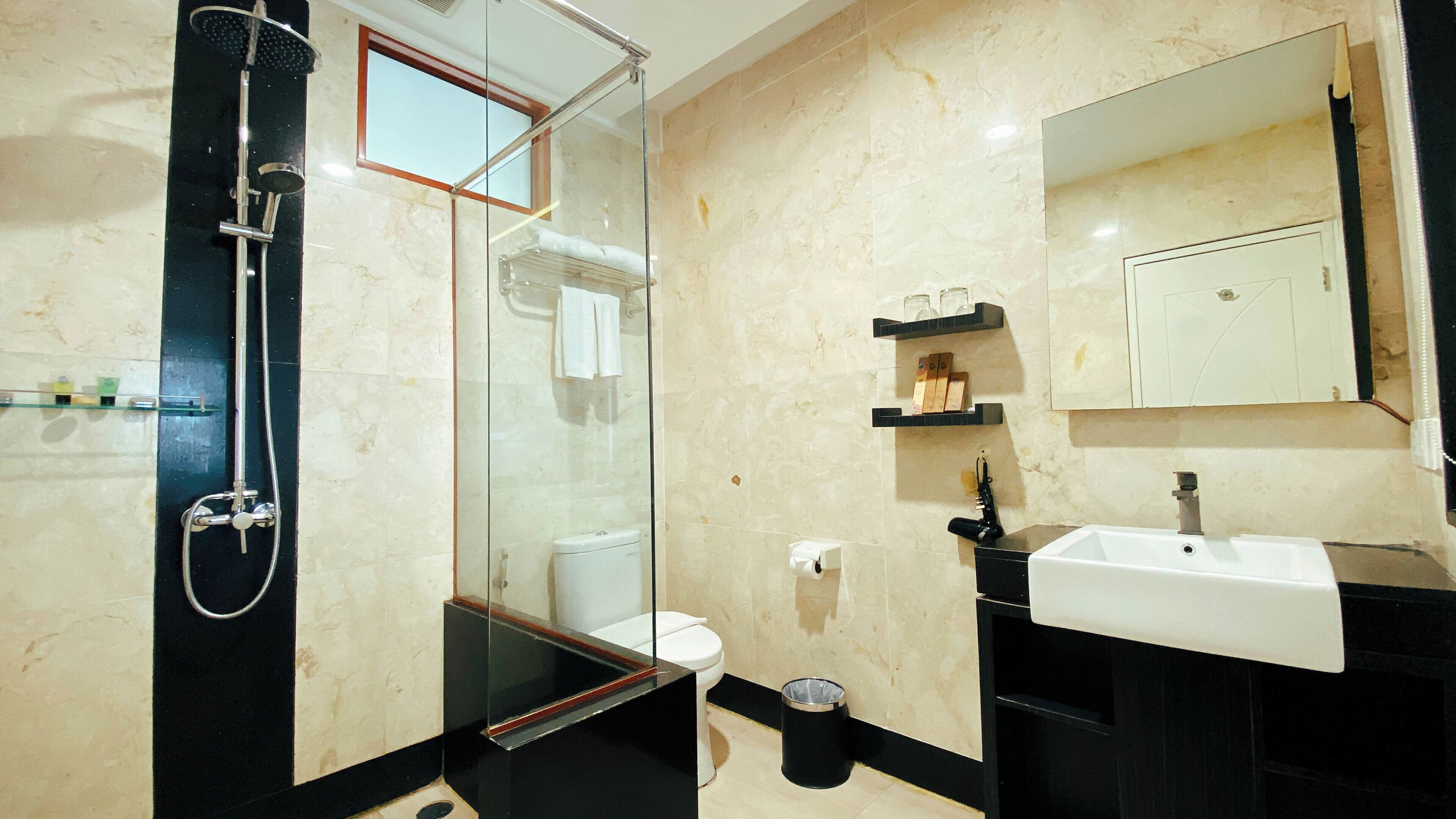 A modern bathroom with a glass-enclosed shower, a toilet, a sink, and a mirror.