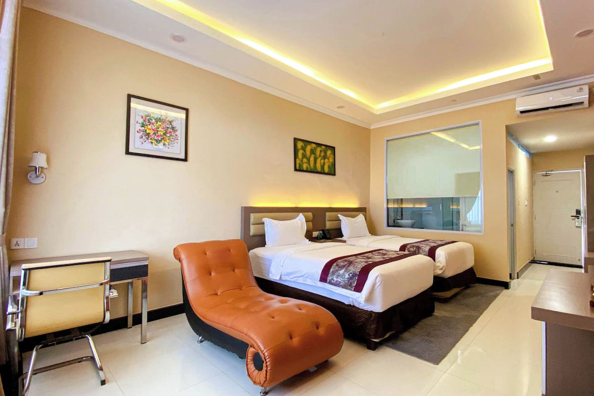 Una habitación de hotel con cama, escritorio, silla y un ventanal grande.