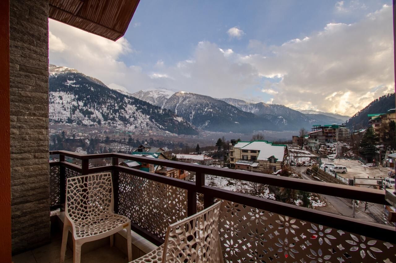 A balcony with a view of snow-covered mountains and a village below.
