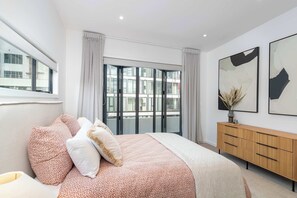 Ein Schlafzimmer mit einem großen Bett, einer Holzkommode und einem Fenster mit Vorhängen.