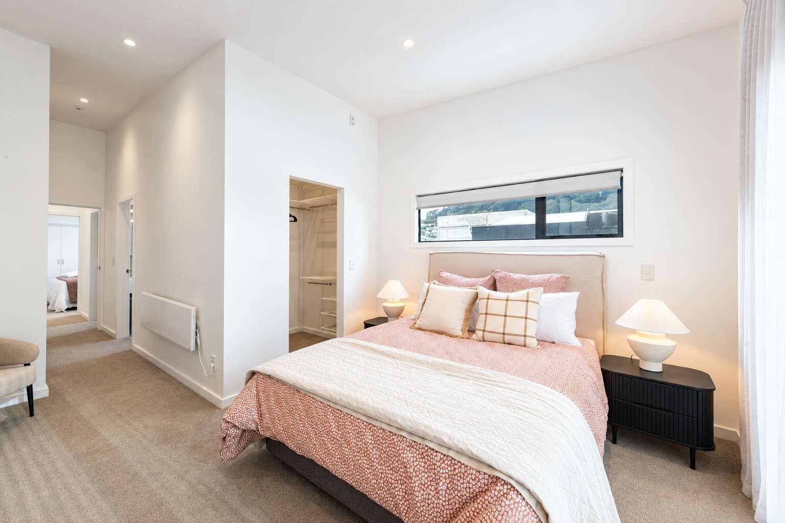 Un dormitorio con cama, lámparas de noche, ventana con vistas y vestidor.