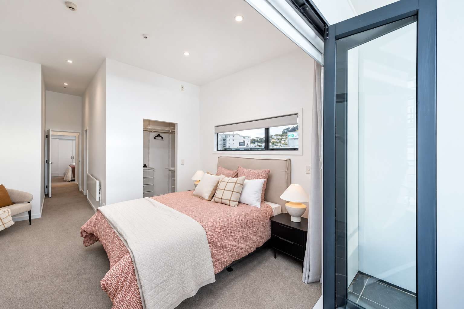 Un dormitorio moderno con una cama, mesitas de noche, un ventanal y vistas al exterior.