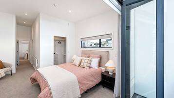 Un dormitorio moderno con una cama, mesitas de noche, un ventanal y vistas al exterior.