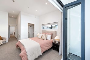 Un dormitorio moderno con una cama, mesitas de noche, un ventanal y vistas al exterior.