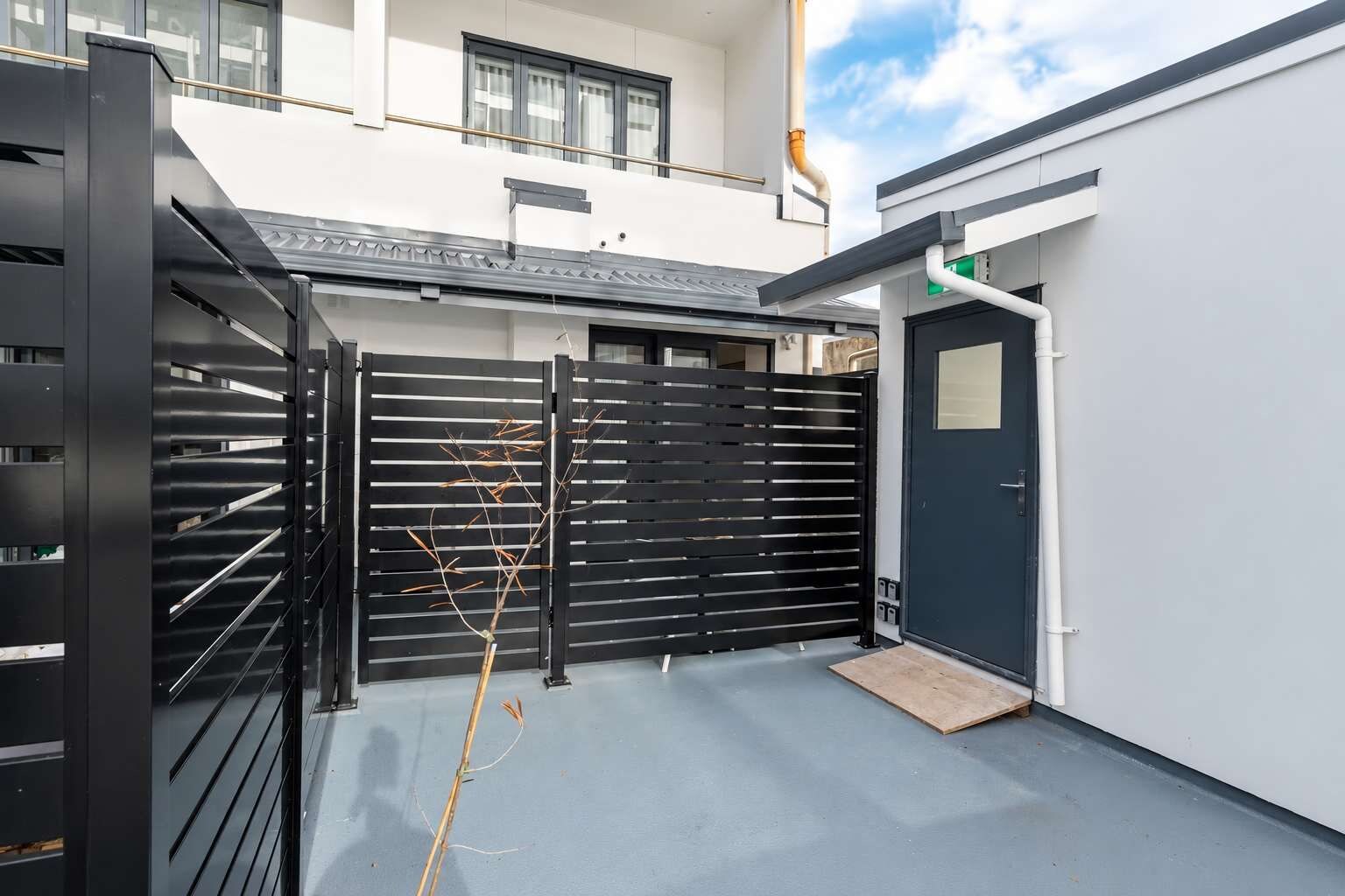 A gated entrance to a building with a flat roof and a door on the right.