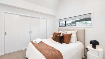 Un dormitorio con cama, mesita de noche, ventana con vistas y armario.