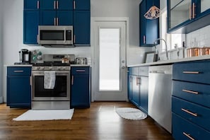 A kitchen with blue cabinets, a microwave, a stove, and a dishwasher.