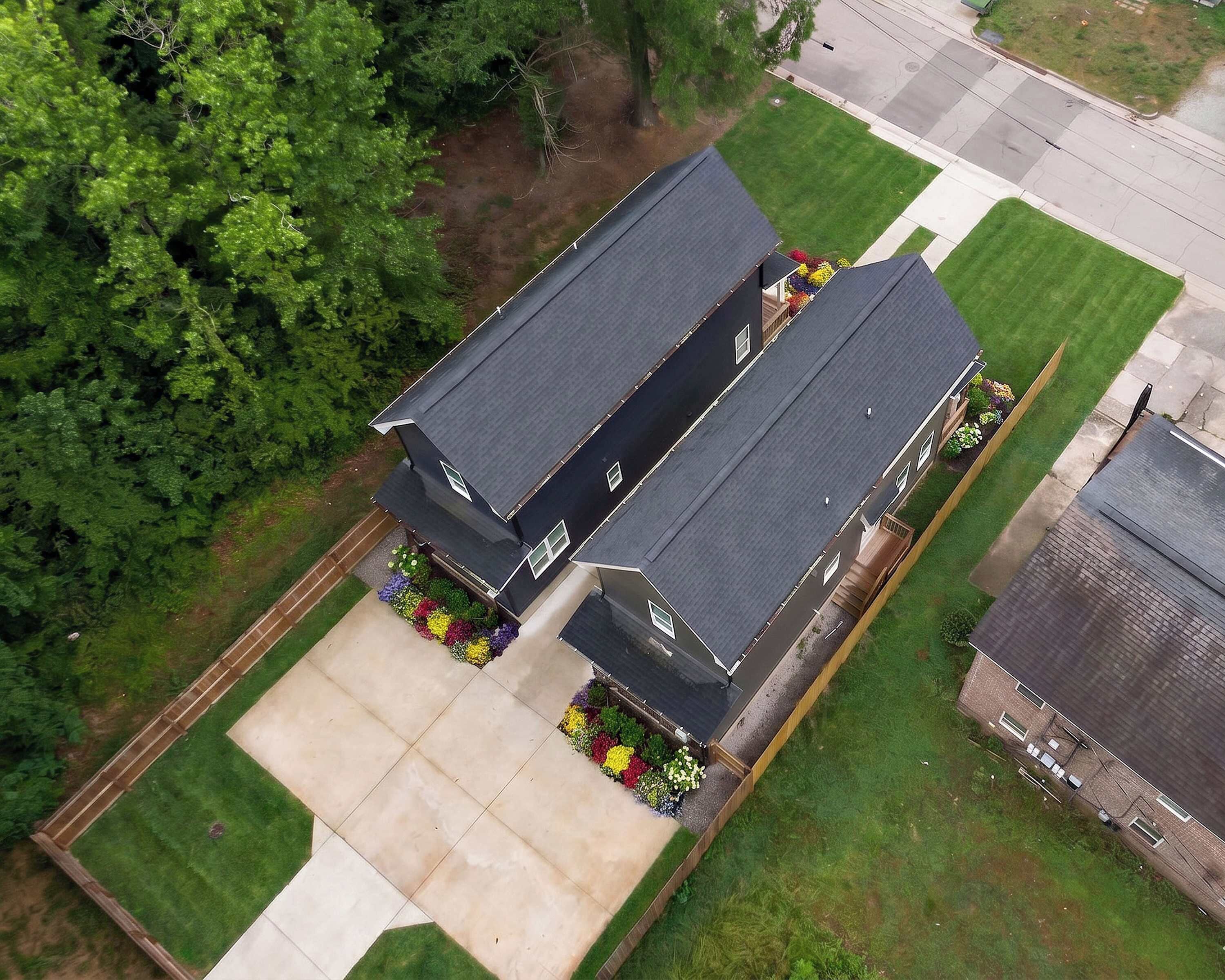 A two-story house with a large front yard, a driveway, and a small garden area.