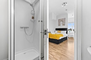 A modern bathroom with a glass shower enclosure, a visible toilet, and a white sink. - Comfort Studio Leeds Ideal for Work Study Street Parking (Leeds)