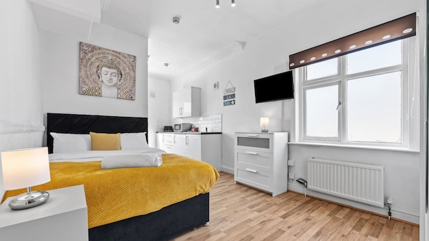 A modern bedroom with a bed, bedside table, and a window with a view. - Comfort Studio Leeds Ideal for Work Study Street Parking (Leeds)
