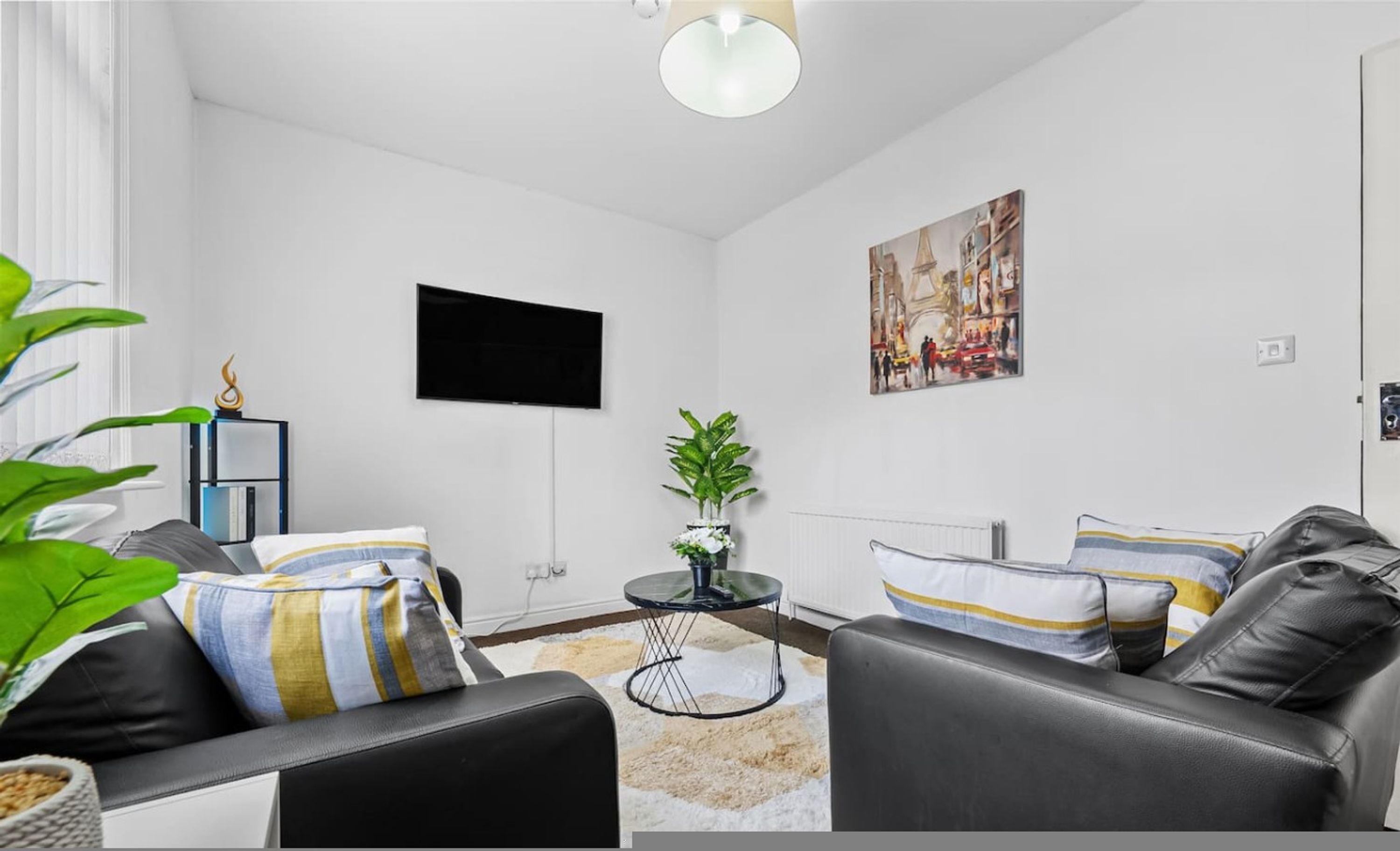 A modern living room with a sofa, a coffee table, a TV, and a painting on the wall.