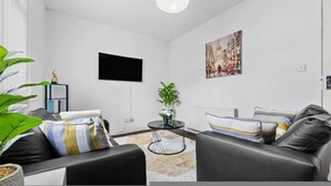 Una sala de estar moderna con un sofá, una mesa de centro, un televisor y un cuadro en la pared.