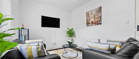 Ett modernt vardagsrum med en soffa, ett soffbord, en tv och en tavla på väggen.