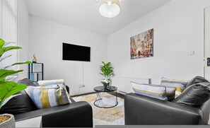 Ein modernes Wohnzimmer mit einer Couch, einem Couchtisch, einem Fernseher und einem Bild an der Wand.