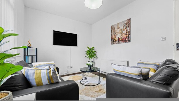 A modern living room with a black leather sofa, a small round table, and a potted plant. - Modern Leeds Studio Retreat Sleeps 2 Street Parking (Leeds)