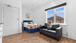 A bedroom with a bed, a sofa, a window with a view, and a door. - Modern Leeds Studio Retreat Sleeps 2 Street Parking (Leeds)
