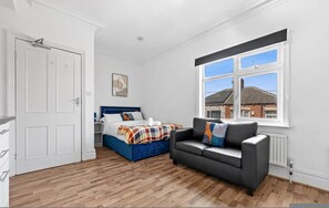 Ein Schlafzimmer mit Bett, Sofa, Fenster und Tür.