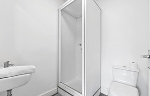 A bathroom with a white sink, a glass shower enclosure, and a white toilet. - Cosy Leeds Studio Ensuite Kitchenette Wifi Street Parking (Leeds)