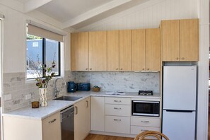 Une cuisine moderne avec des meubles en bois, un four encastré et un réfrigérateur en acier inoxydable.