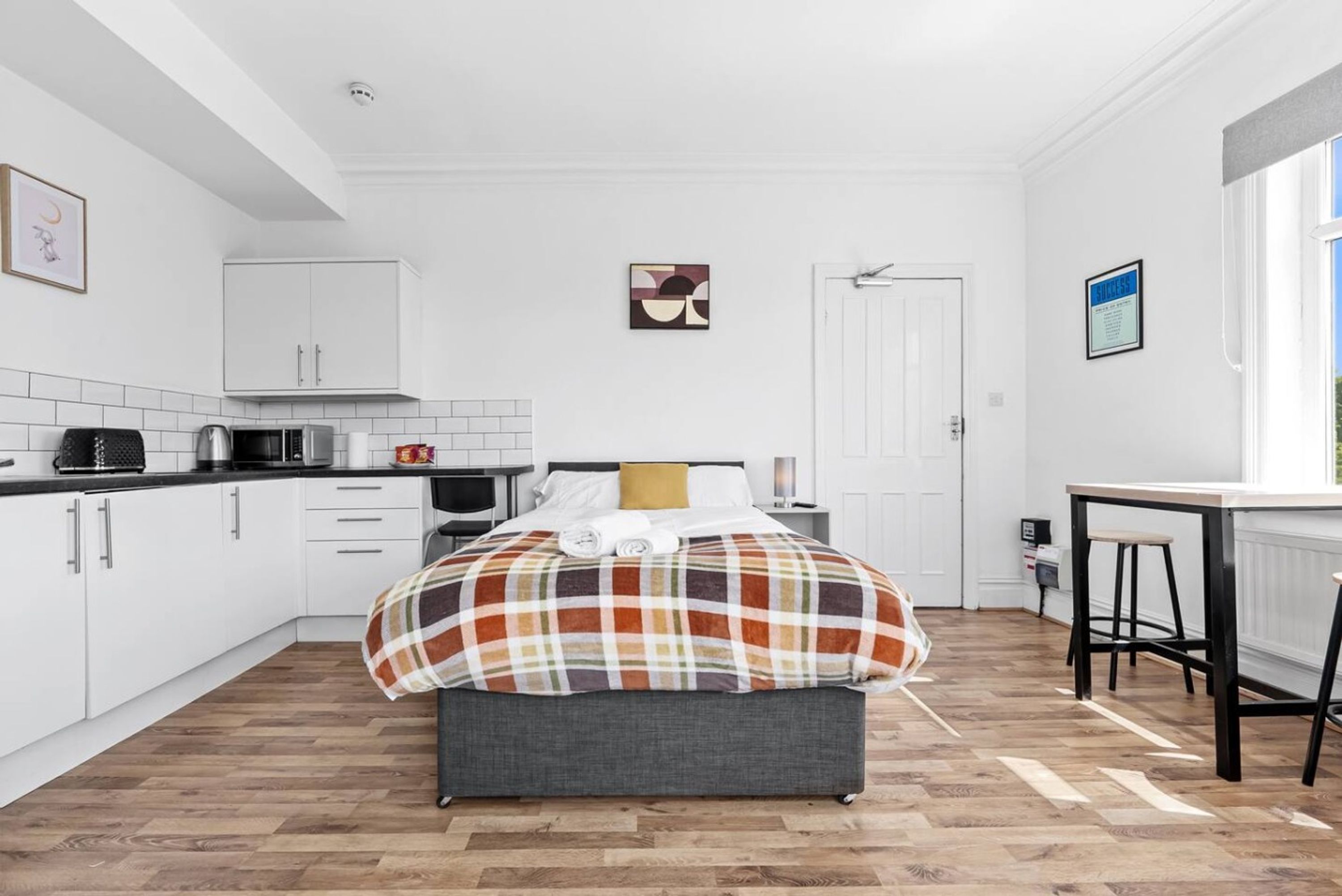 A modern kitchen with white cabinets, a microwave, and a coffee maker.