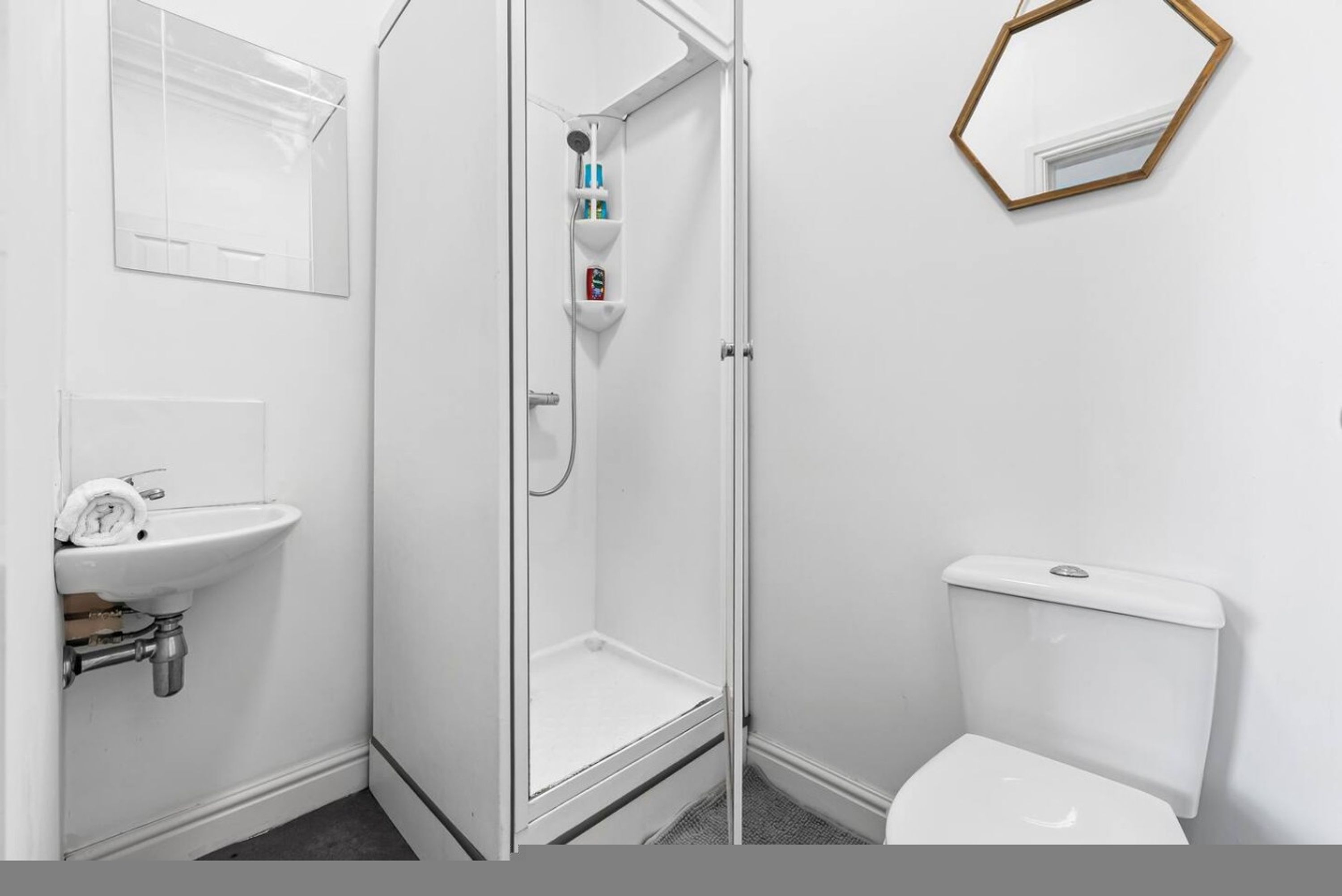 A bathroom with a shower, toilet, sink, and a mirror.