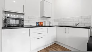 A modern kitchen with white cabinets, a microwave, and a sink. - Large Modern Leeds Stay w 8 Private Ensuite Studio (Leeds)
