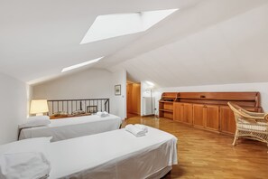 A room with two beds, a wooden cabinet, a wicker chair, and skylights. - Apt. Annamaria: Family-friendly 2BR Central Base for Trips (Laveno Mombello)