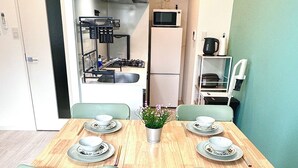 Une cuisine compacte dotée d’appareils électroménagers modernes, une table à manger avec des chaises et un petit réfrigérateur.