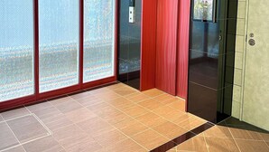 Un ascenseur moderne doté d’un écran numérique, d’une porte rouge et d’une paroi en verre offrant une vue dégagée.