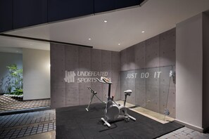 Et moderne fitnesscenter med motionscykler, en væg med motiverende tekst og et flisegulv.