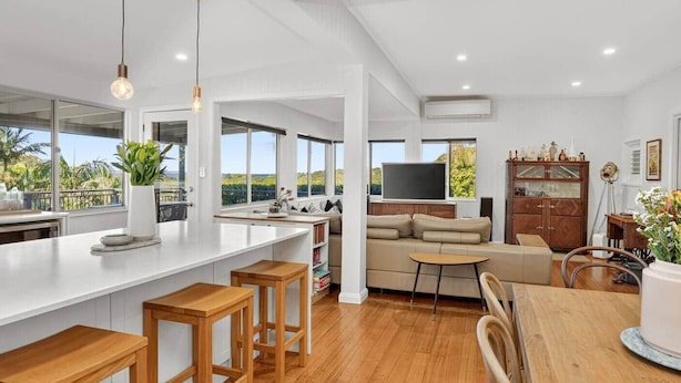 Una cocina moderna con una isla grande, taburetes de madera y una mesa de comedor.