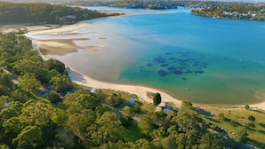 Vista aérea de una zona costera con playa, aguas cristalinas y vegetación circundante.