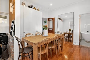 A dining area with a wooden table and chairs, a white cabinet, and a mirror.