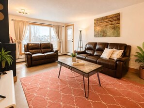 A living room with two leather sofas, a coffee table, a floor lamp, and a painting on the wall. - Charming 2Bd Apartment in Downtown Calgary (Calgary)