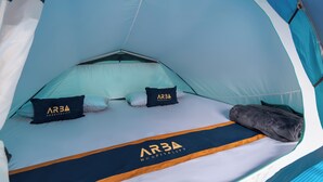 Tienda de campaña con una cama en su interior, mostrando un logotipo en la almohada y la manta.