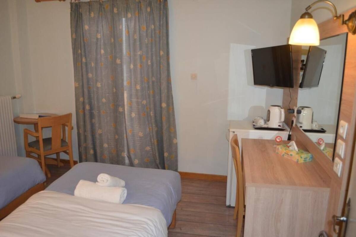 Habitació d'hotel amb dos llits, escriptori, cadira, televisió i mirall.