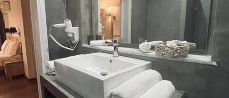 Une salle de bain moderne avec un grand lavabo, un miroir et un porte-serviettes.