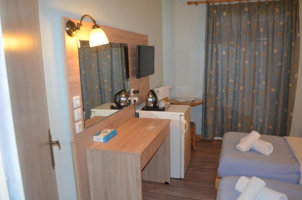 Ett hotellrum med ett skrivbord i trä, en tv, en säng och en duschhörna.