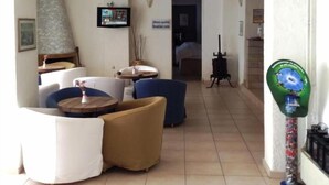 Una sala de estar con un sofá, una mesa de centro y una televisión. Hay una puerta que da a otra habitación.