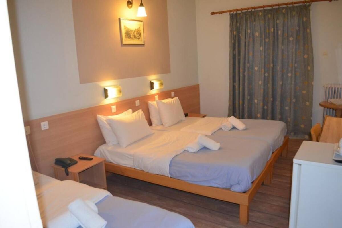 Habitació d'hotel amb llit doble, taules de nit, escriptori i cortina amb motius florals.